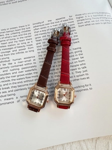 Close-up of square women's watches with leather straps on a vintage book page