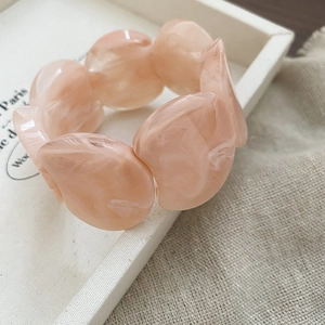 Close-up of pink acrylic resin chunky bead bracelet with marble texture on white tray