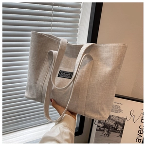 Detailed texture of high-capacity canvas tote bag in beige shown in natural window light