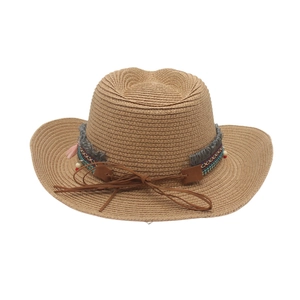 Close-up of bohemian woven straw hat with colorful ethnic bands and pink tassels