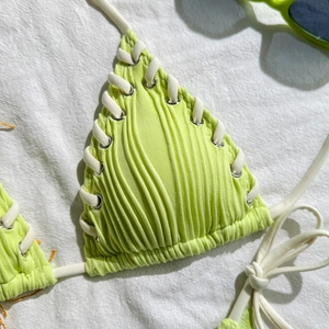 Detail of lime green ribbed bikini top with white side lace-up and metal eyelets