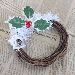 Gros plan de couronne de rotin de Noël avec feuilles vertes et baies rouges d'hiver