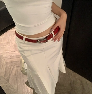 Détail d'une ceinture en cuir rouge à texture crocodile et boucle ovale argentée