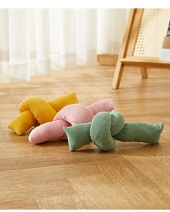 Tres cojines de nudo en pana de color amarillo rosa y verde sobre suelo de madera