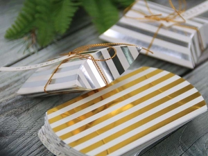 Detail of striped pillow gift boxes with gold cord and Thank You labels on wood