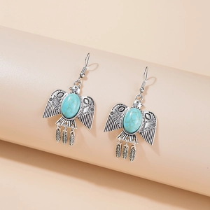 Macro shot of bronze eagle earrings with turquoise inlays and hanging feather charms