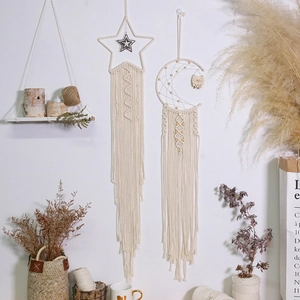 Detail of handmade macrame star and moon dreamcatchers with long cotton tassels on wall