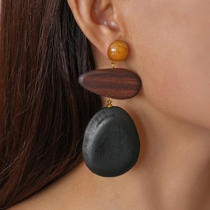 Close-up of model wearing three-tier resin and wood drop earrings with gold connectors