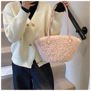 Détail d'un sac à main rose en fausse fourrure montrant la texture douce et l'anse