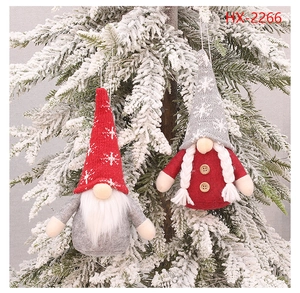 Detailed Christmas gnome ornaments hanging on snowy pine branches with knitted hats