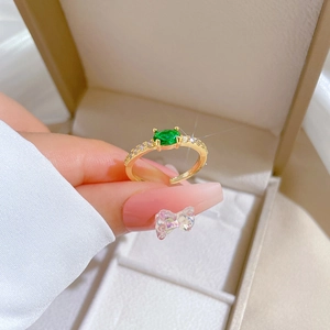 Adjustable gold ring with green oval zircon and side diamonds on a jewelry box background