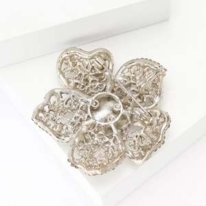 Vue détaillée du dos d'une broche fleur argentée montrant le filigrane et l'épingle