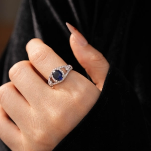 Macro detail of silver ring featuring oval blue gemstone and micro-pave side diamonds