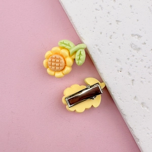 Close-up of yellow sunflower hair clips with green leaves and silver metal clips