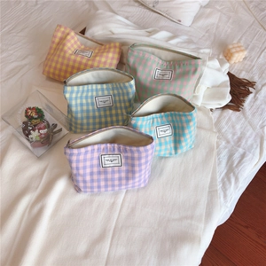 Flat lay of colorful checkered canvas makeup bags with Time to Party labels on bed