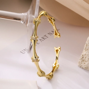 Minimalist gold plated bamboo joint cuff bracelet with zircon accents on a glass