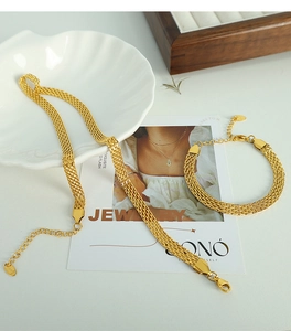 Detail of gold mesh woven necklace and bracelet set displayed on a white shell tray