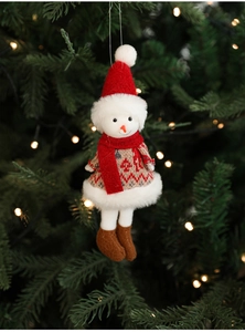 Close-up of plush snowman ornament with red hat and knitted sweater on Christmas tree