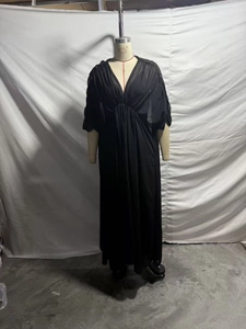Detail eines eleganten schwarzen Kleides mit V-Ausschnitt, Raffungen und transparentem Stoff