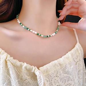 Detailed close-up of malachite and pearl beaded necklace on a model collarbone