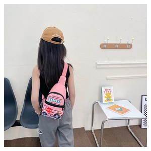 Pink school bus chest bag for kids worn by a child in a cozy home setting
