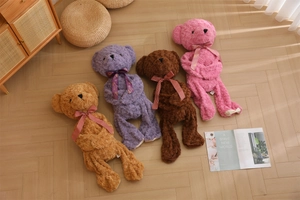 Detail of four colorful plush teddy bears with ribbons on a wooden floor background