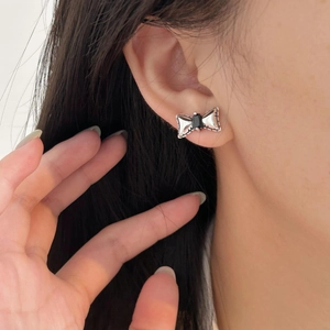 Detailed close-up of a silver bow earring featuring a rectangular black zircon gemstone