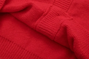 Nahaufnahme des roten Strickpullovers mit Rippbündchen und weicher Fasertextur im Detail