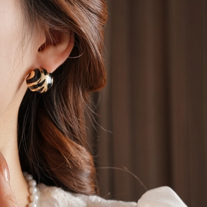 Close-up of model wearing round tiger pattern earrings in black and gold finish