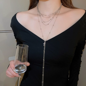 Detail of multilayer silver chain necklace with zircon cross pendant on a model