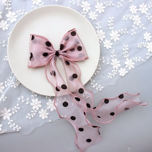 Detailed view of pink polka dot organza hair bow clip with long flowing ribbons