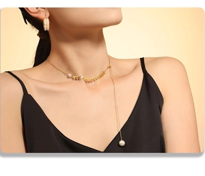 Close-up of 18k gold plated wheat pendant necklace and pearl earrings on a model