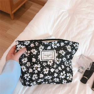 Detail of black floral seersucker cosmetic bag with daisy pattern and woven label