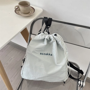 Close-up of lightweight drawstring backpack in light blue-grey on a modern chair