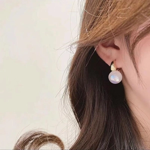Elegant gold hoop earrings with white spherical pearl drop pendants on female model