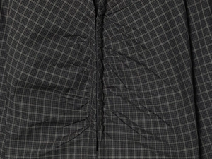 Detail of dark grey plaid fabric showing intricate ruching and woven texture details