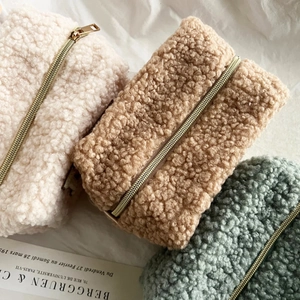 Lammwoll-Kosmetiktaschen in Creme, Khaki und Grün mit goldenen Reißverschlüssen im Detail