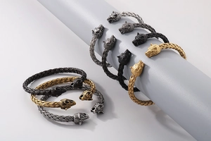 Detail of woven stainless steel cuffs with animal head charms in silver, black and gold