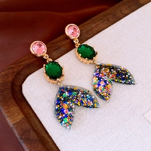 Dettaglio di orecchini a coda di sirena con cristalli colorati e paillettes brillanti