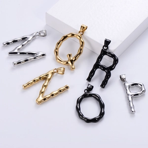 Close-up of alphabet pendants with fluid texture in gold, silver, and black finish