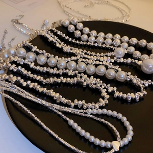 Detail view of silver irregular beads and faux pearl necklaces on a black tray