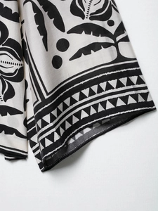 Détail du poignet d'une chemise imprimée avec motifs de feuilles noires et blanches sur tissu