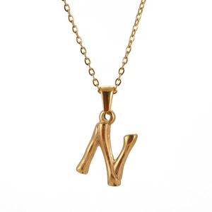 Detail of gold letter N pendant with unique bamboo texture on polished stainless steel
