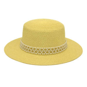 Detailed texture of woven straw boater hat featuring elegant pearl cross band decoration