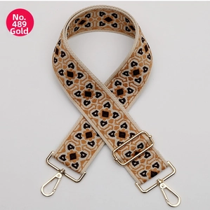 Detail of adjustable ethnic style beige guitar strap with gold geometric pattern and hardware