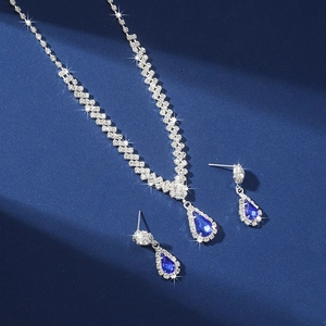 Macro detail of silver-tone teardrop necklace and earring set with deep blue crystals