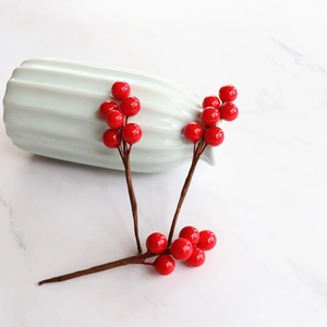 Artificial red berry decorative branch for DIY home decor on white marble surface