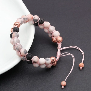 Dettaglio di perle in marmo rosa e pietra lavica con accenti in oro rosa su cordino