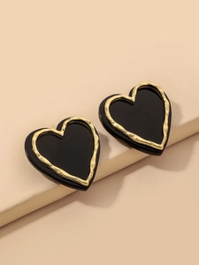 Macro shot of black acrylic heart earrings with textured golden metallic borders