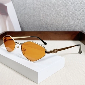 Retro geometric metal sunglasses with orange resin lenses and gold frames on a display stand